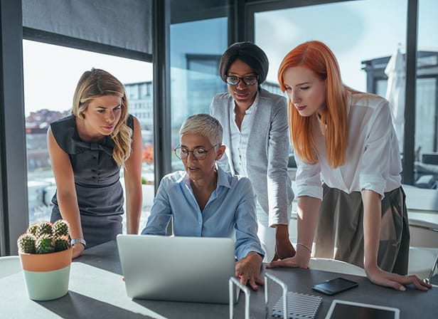 Women team looking at a laptop in an office