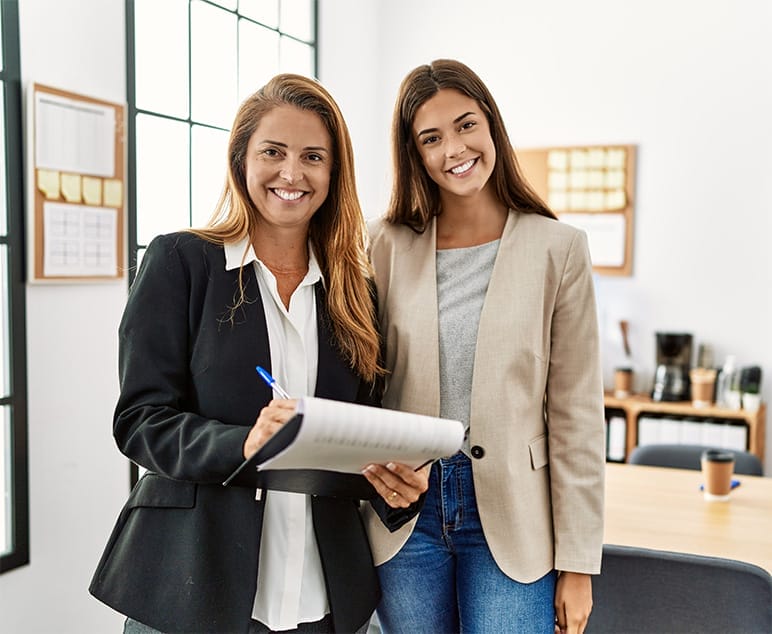 Partner Brands Hero Two smiling women standing side by side in an office