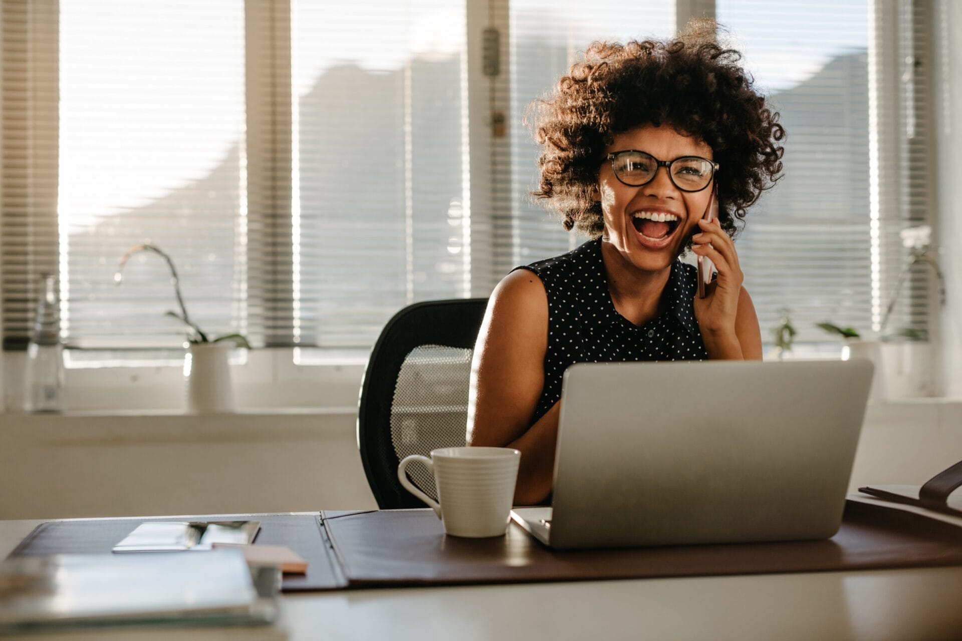 woman on phone laughing at desk