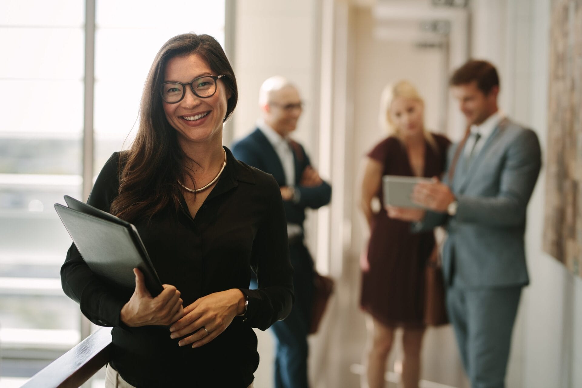 woman with folder with colleagues behind