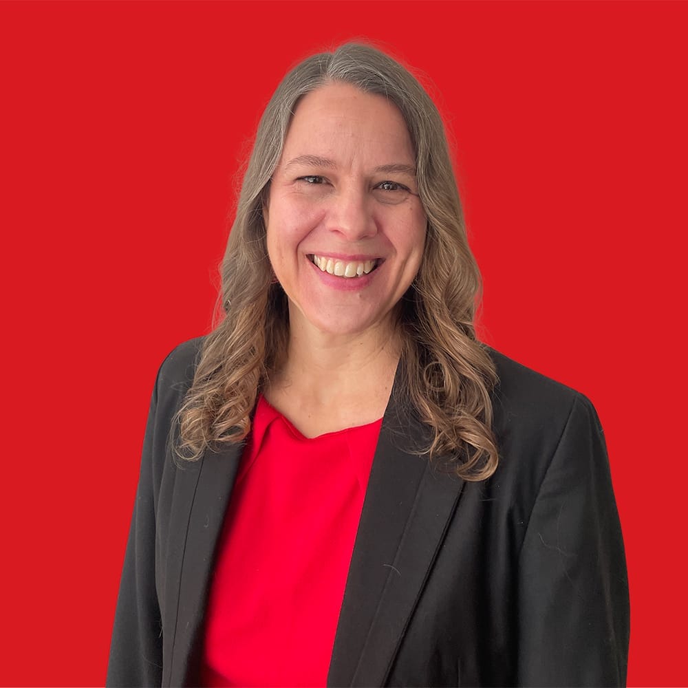 A head shot of Karen Surmon smiling and a red background