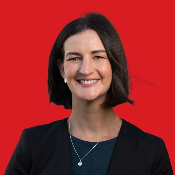 A headshot of Ellen Sandell in a red background