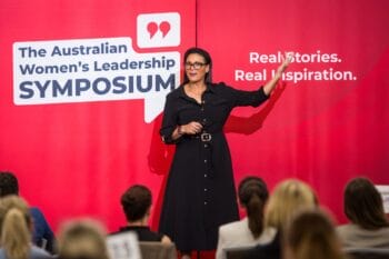 A speaker presenting on stage at the Brisbane Symposium